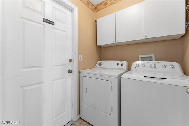 washroom featuring cabinets, light tile patterned floors, and washing machine and clothes dryer