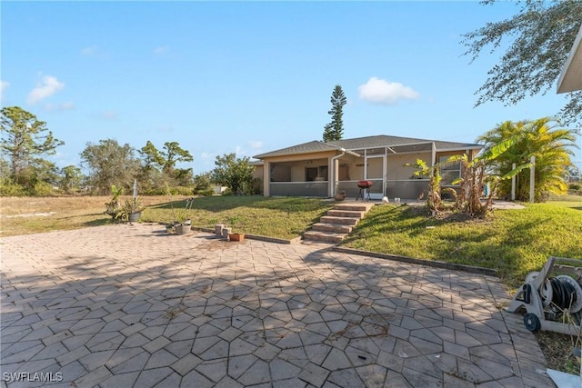 back of property featuring a patio, a sunroom, and a lawn