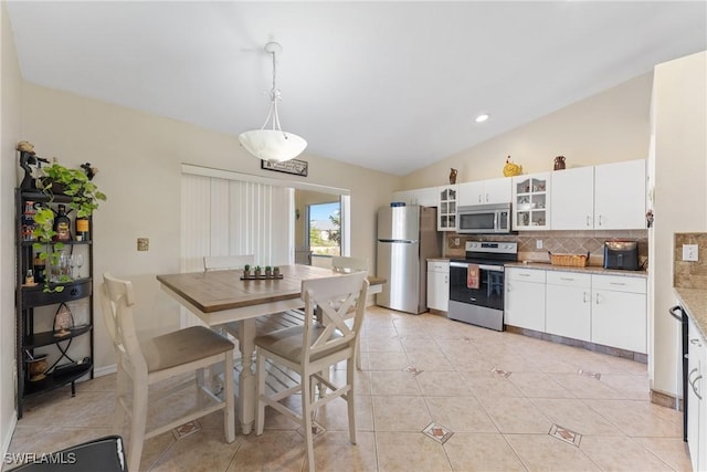 kitchen featuring pendant lighting, white cabinets, vaulted ceiling, tasteful backsplash, and stainless steel appliances