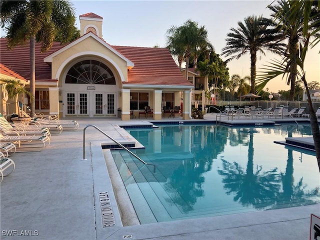 pool at dusk featuring a patio