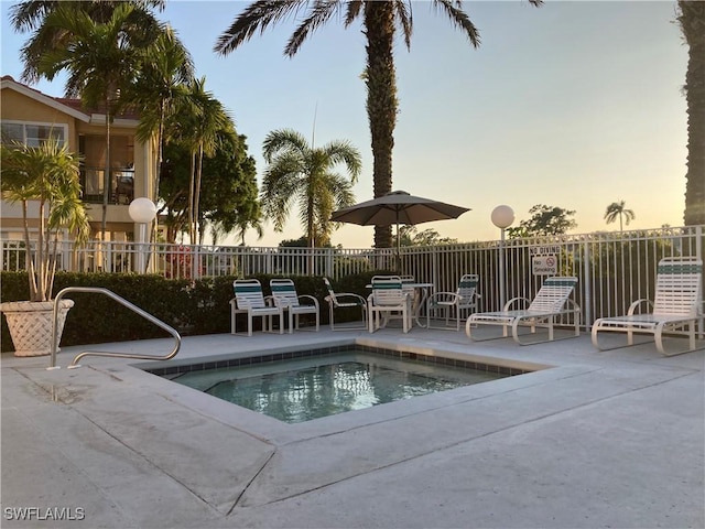 pool at dusk featuring a patio