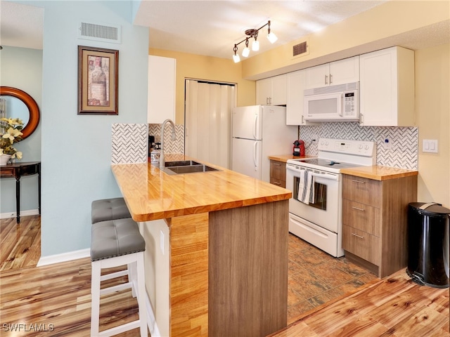 kitchen featuring white appliances, a kitchen bar, white cabinetry, tasteful backsplash, and sink