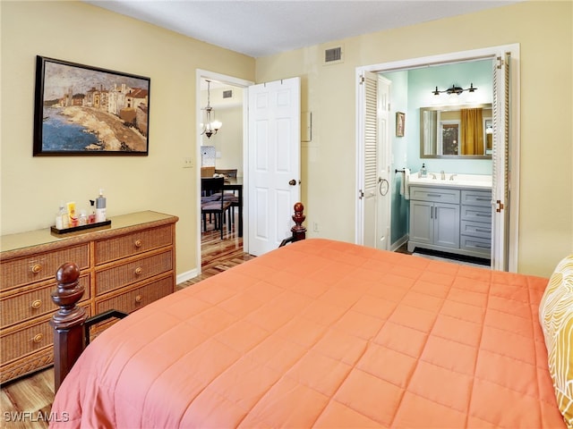 bedroom featuring ensuite bath, sink, and an inviting chandelier