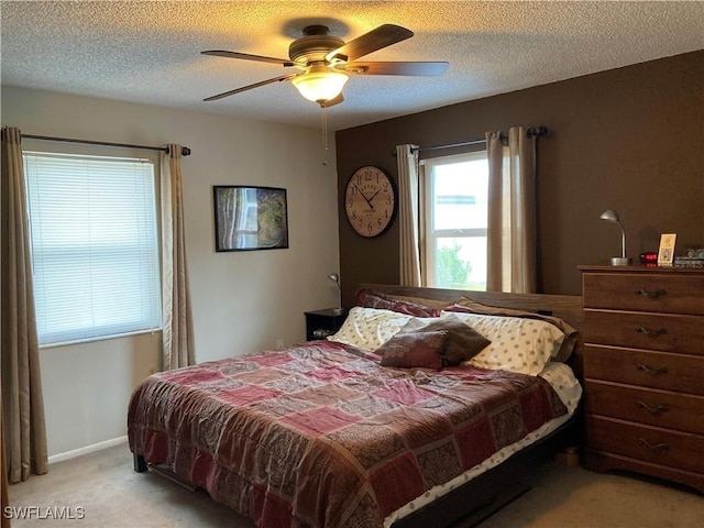 bedroom with ceiling fan, light carpet, and a textured ceiling