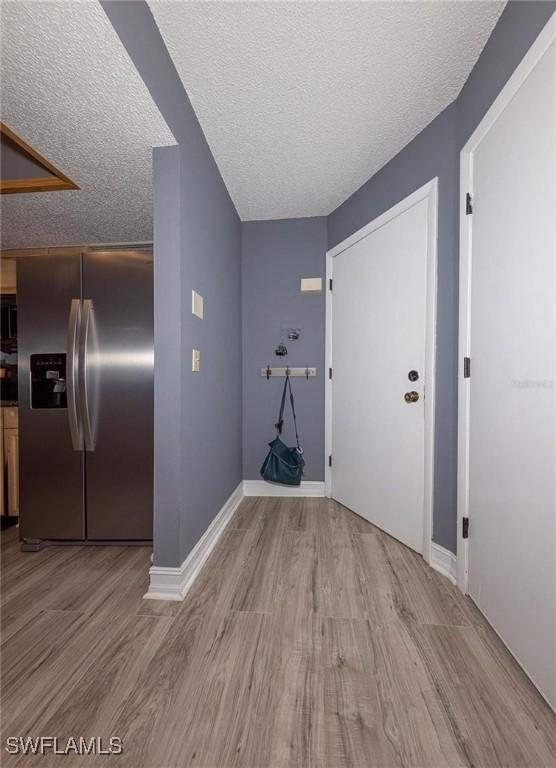 clothes washing area with light hardwood / wood-style flooring and a textured ceiling