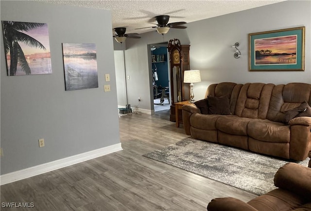 living room featuring hardwood / wood-style flooring, ceiling fan, and a textured ceiling