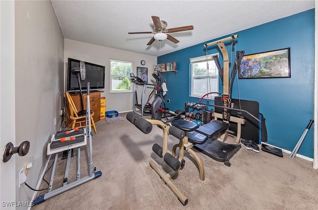 workout room with ceiling fan, carpet flooring, and a textured ceiling