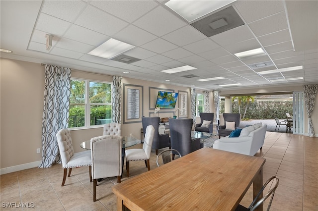 dining space featuring a healthy amount of sunlight, light tile patterned floors, baseboards, and a drop ceiling