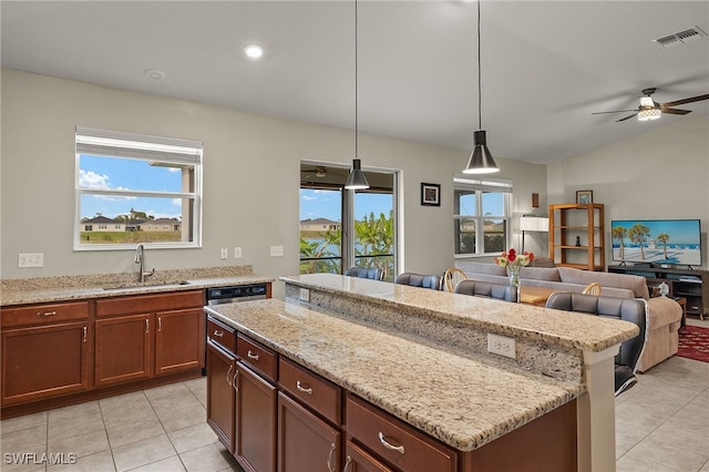 kitchen with a center island, open floor plan, a sink, and light stone countertops