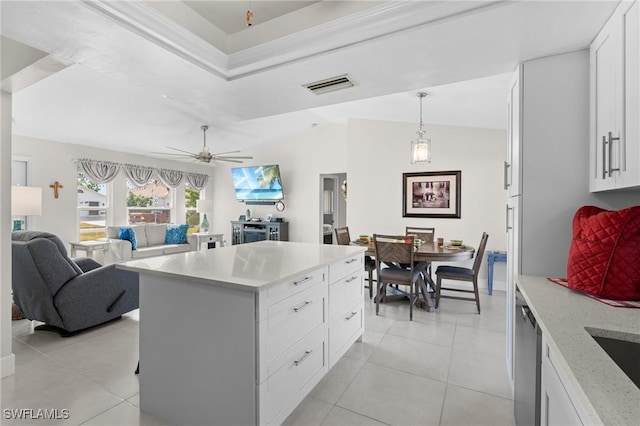 kitchen with ceiling fan, light tile patterned floors, decorative light fixtures, a center island, and white cabinetry