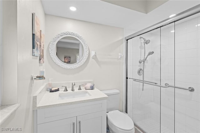 bathroom featuring vanity, toilet, and a shower with shower door