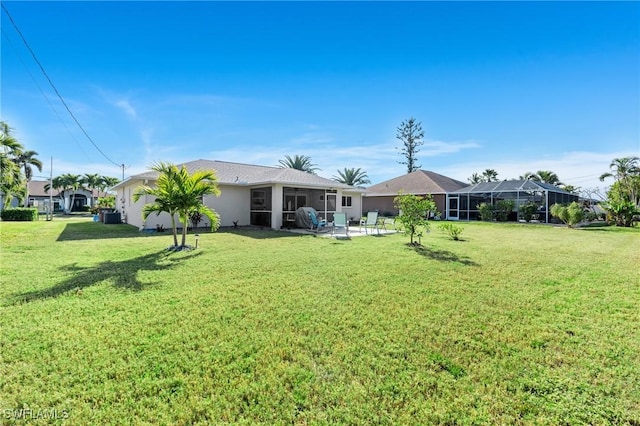 rear view of property featuring a lawn, a sunroom, a patio, and a lanai