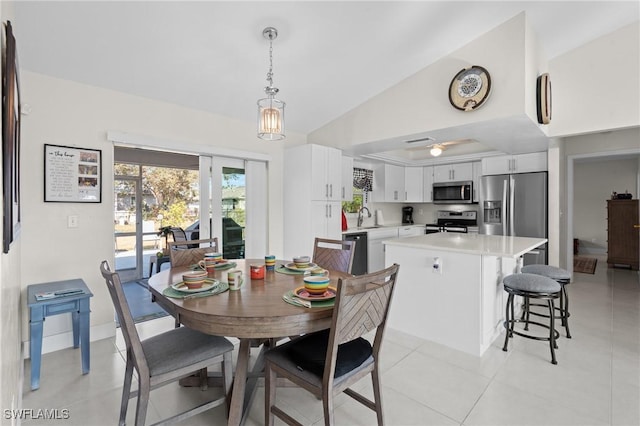 tiled dining area featuring sink and lofted ceiling