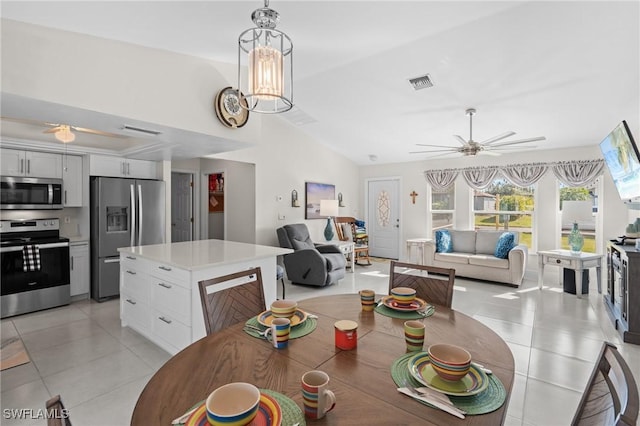 tiled dining room featuring ceiling fan with notable chandelier and vaulted ceiling