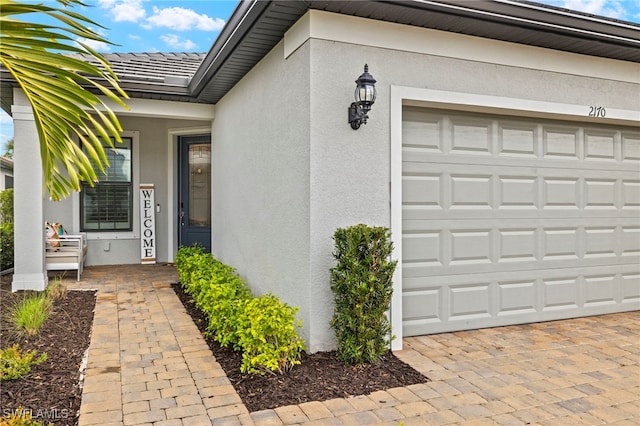 entrance to property with an attached garage and stucco siding