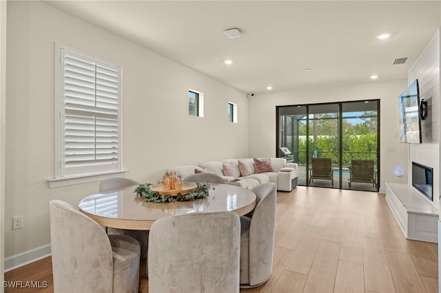 dining area with a large fireplace, visible vents, baseboards, light wood-style flooring, and recessed lighting