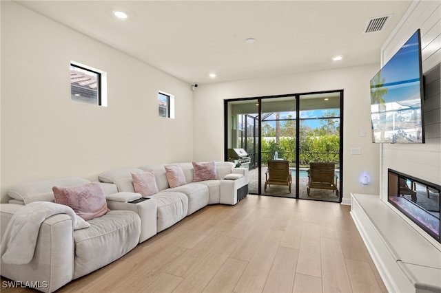 living room featuring light wood-style floors, visible vents, a large fireplace, and recessed lighting