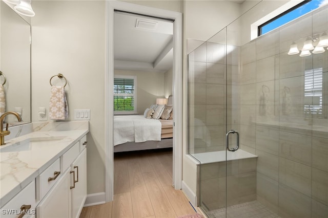 ensuite bathroom with visible vents, connected bathroom, a shower stall, vanity, and wood finished floors