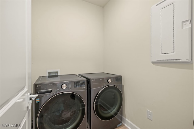 clothes washing area with laundry area, baseboards, and separate washer and dryer