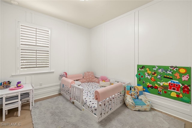 bedroom featuring light wood-style floors and a decorative wall