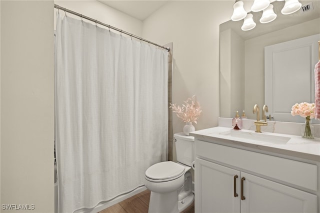 bathroom featuring toilet, vanity, wood finished floors, and visible vents