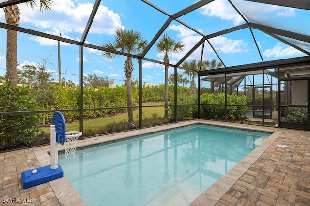 outdoor pool featuring glass enclosure and a patio