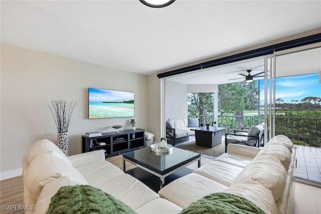 living room featuring ceiling fan, a wall of windows, and hardwood / wood-style flooring