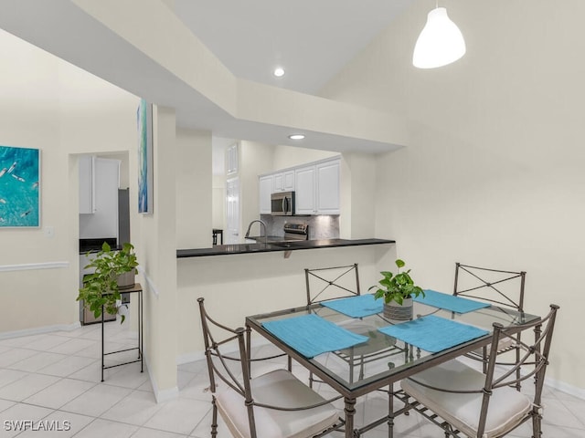 dining area with sink, a towering ceiling, and light tile patterned floors