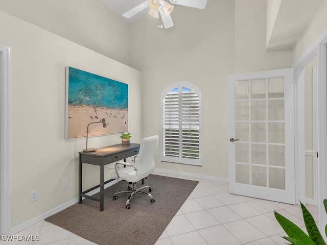 tiled home office with ceiling fan and a high ceiling