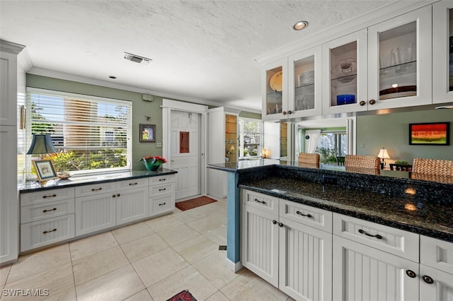 kitchen featuring white cabinetry, ornamental molding, and dark stone counters