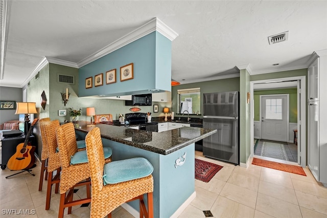 kitchen with light tile patterned floors, sink, kitchen peninsula, and black appliances