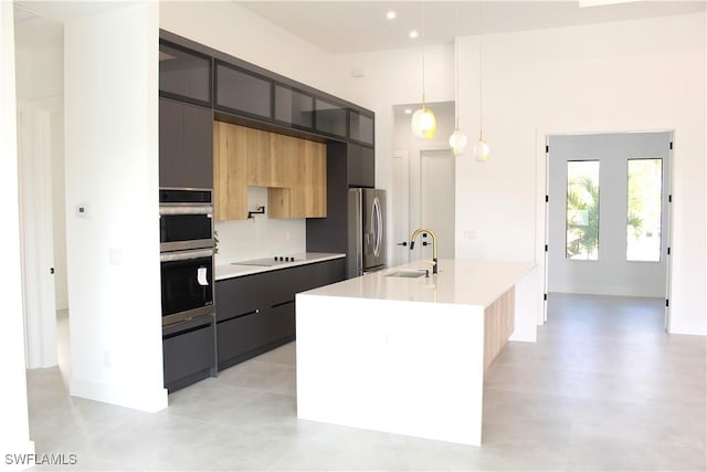 kitchen with hanging light fixtures, a kitchen island with sink, appliances with stainless steel finishes, and sink