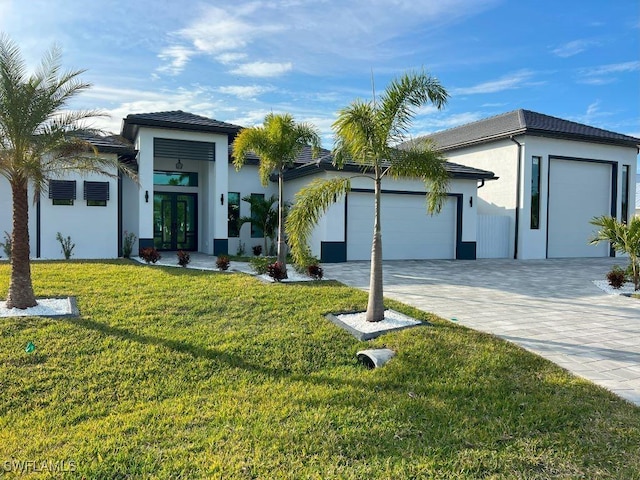 view of front facade with a front yard, a garage, and french doors