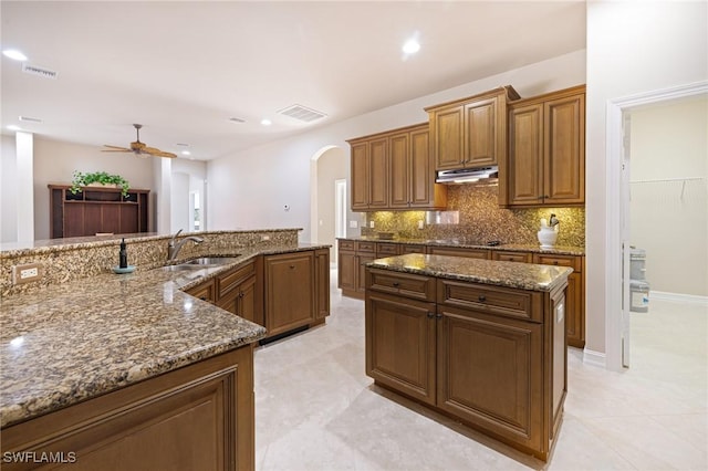 9284 Trieste Dr, Fort Myers, FL 33913 - kitchen with under cabinet range hood, a sink, arched walkways, visible vents, and ceiling fan