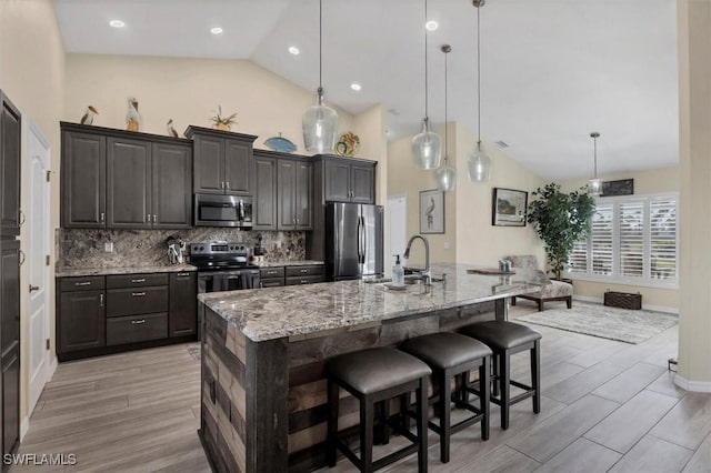 kitchen featuring a kitchen bar, decorative light fixtures, appliances with stainless steel finishes, and a large island