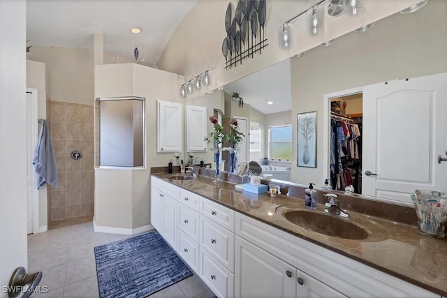 bathroom with a shower, vaulted ceiling, tile patterned floors, and vanity