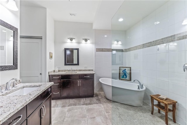 bathroom with vanity, a tub to relax in, and tile walls