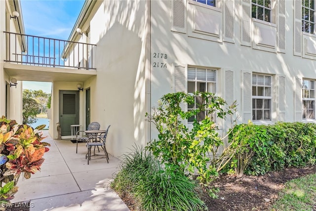 property entrance with a patio, a balcony, and stucco siding