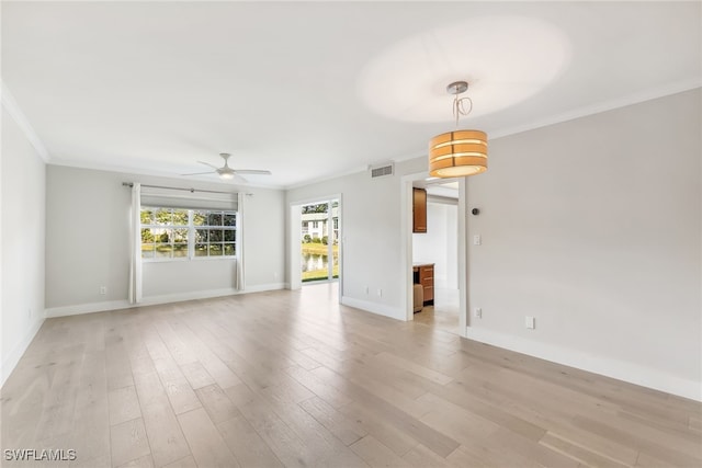 unfurnished room with visible vents, ornamental molding, ceiling fan, light wood-type flooring, and baseboards