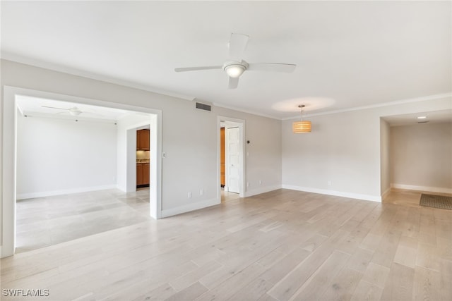 empty room with crown molding, light wood finished floors, visible vents, ceiling fan, and baseboards