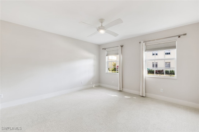 carpeted spare room with a ceiling fan and baseboards