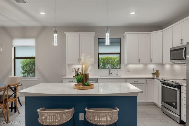 kitchen featuring decorative light fixtures, sink, white cabinetry, and appliances with stainless steel finishes