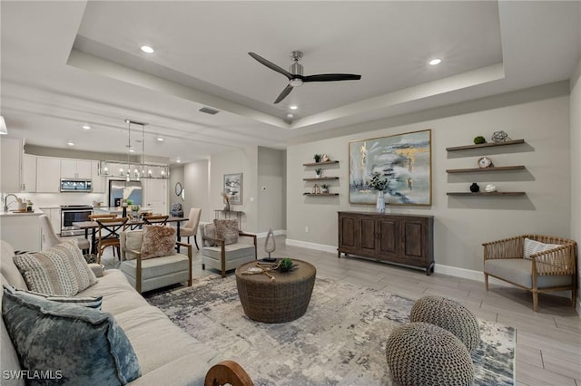 living room featuring ceiling fan and a raised ceiling