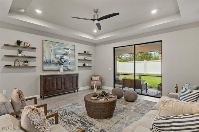 living room featuring ceiling fan and a tray ceiling