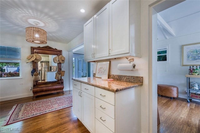 kitchen with dark wood-type flooring, white cabinetry, and light stone counters