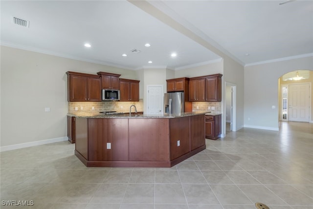 kitchen with ornamental molding, a center island with sink, stainless steel appliances, and light tile patterned flooring