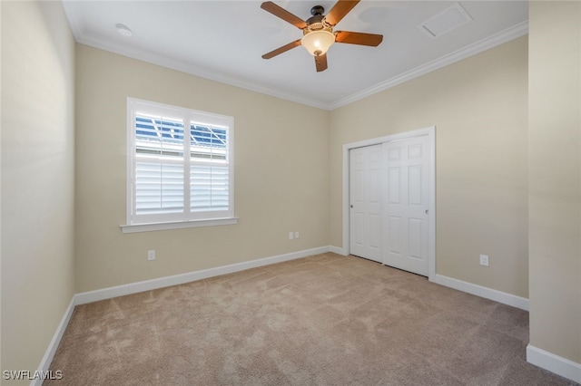 unfurnished bedroom featuring ceiling fan, light carpet, crown molding, and a closet