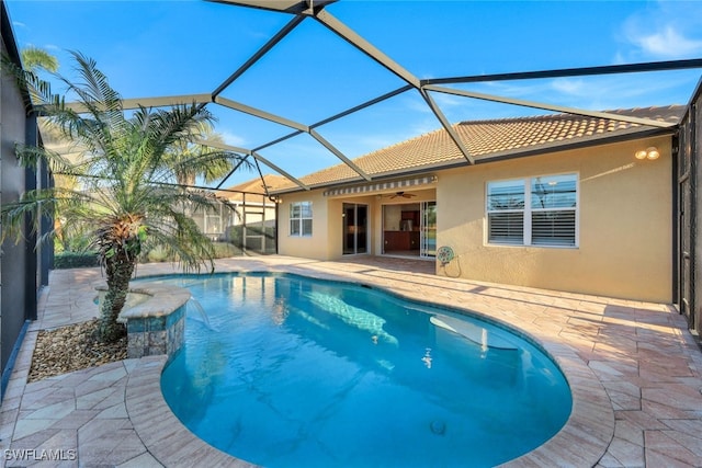 view of swimming pool with ceiling fan, glass enclosure, and a patio area