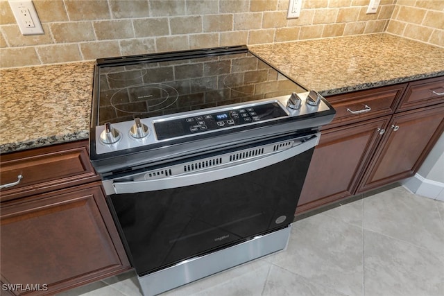 kitchen featuring stainless steel electric stove, light tile patterned floors, decorative backsplash, and light stone counters