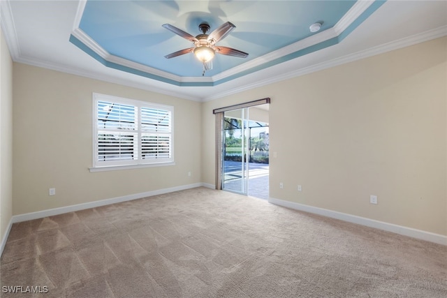 carpeted empty room with ceiling fan, ornamental molding, and a tray ceiling